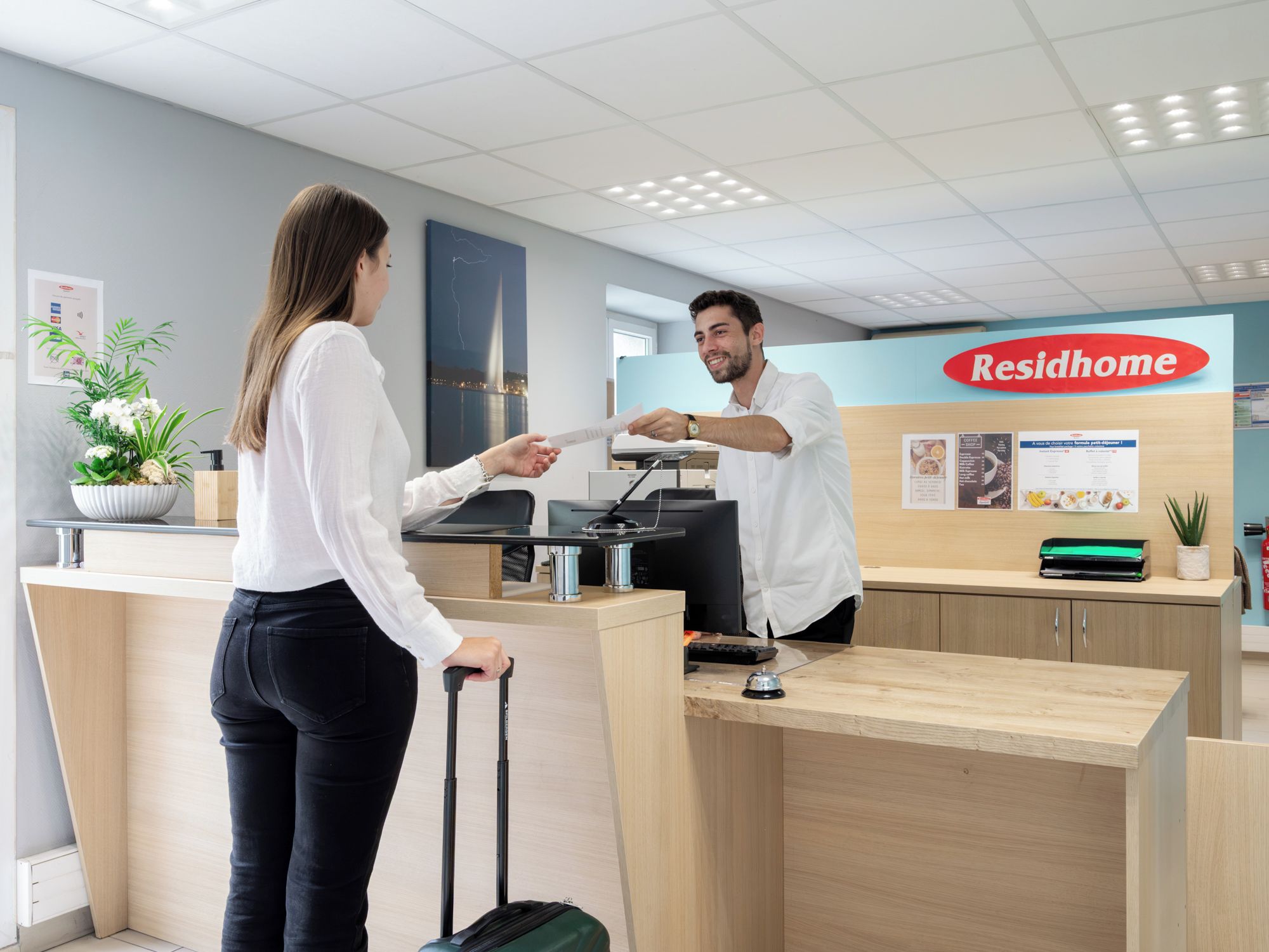 A reception desk with a 'Residhome' sign, a computer, and a plant.