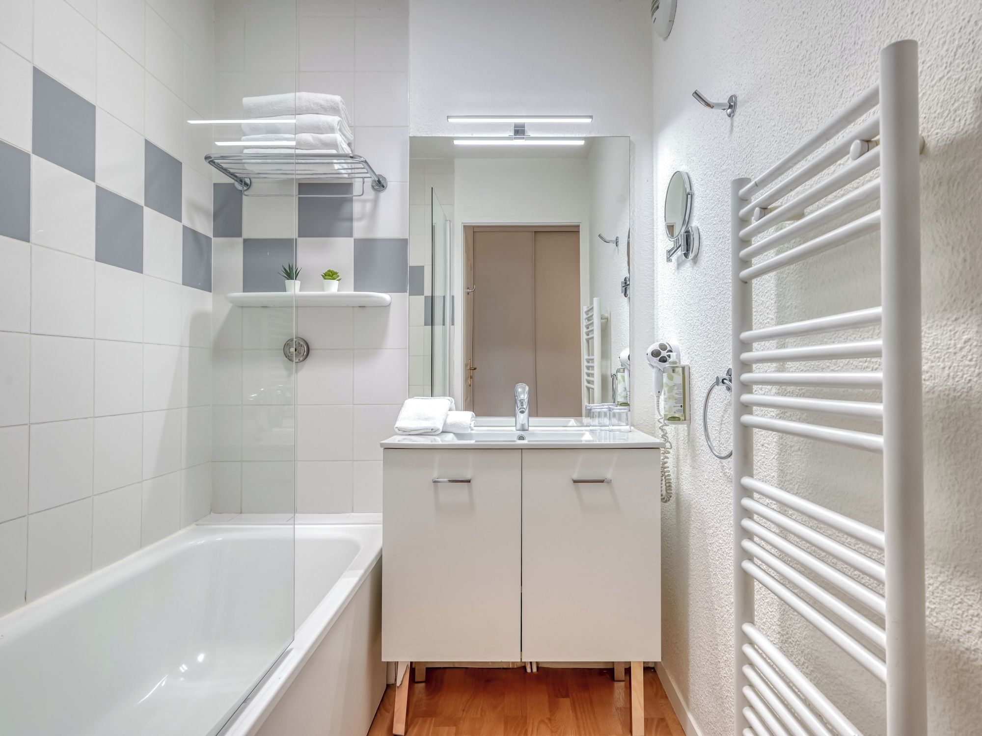 A modern bathroom with a bathtub, a sink, a mirror, and a towel rack.