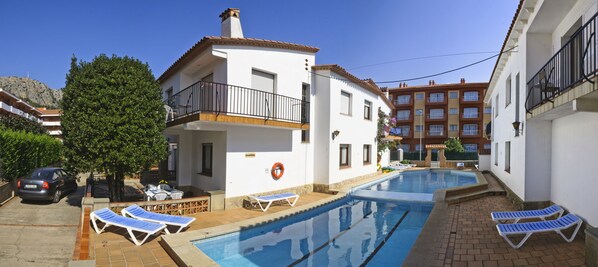 A residential building with a swimming pool, a balcony, and a car parked nearby. - RVApartaments Villas Piscis (Torroella de Montgrí)