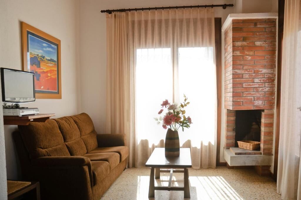 A living room with a sofa, a table with a vase, a fireplace, and a television on a stand.