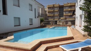 A swimming pool with steps leading into it, surrounded by a white building with balconies. - RVApartaments Villas Piscis (Torroella de Montgrí)