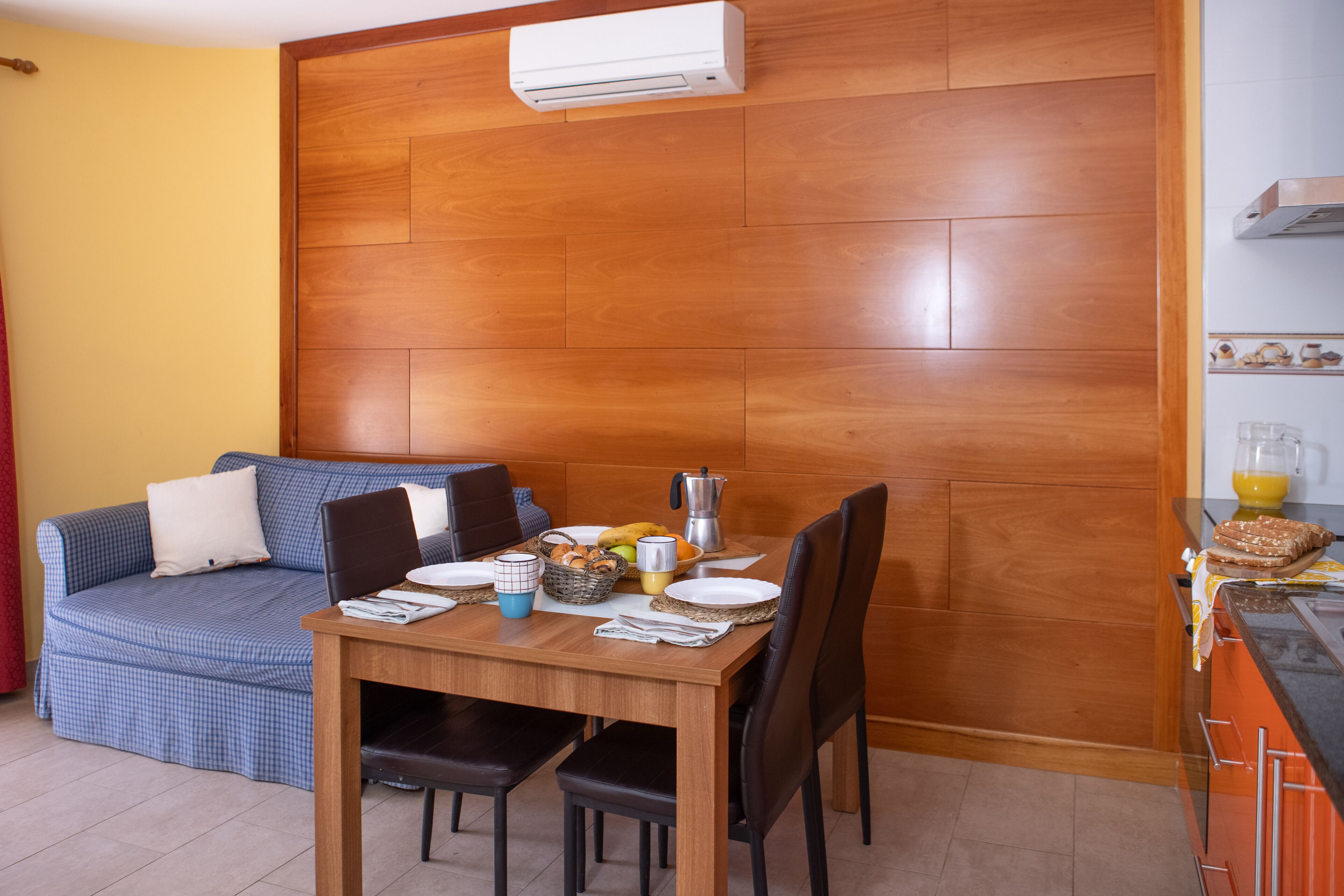 Un espace de vie compact, agrémenté d’une cloison en bois, d’une table à manger dressée avec des assiettes, des tasses et un panier de pain.