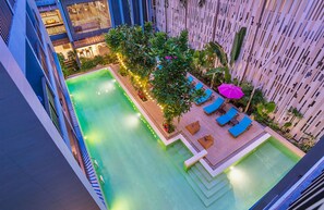 Un espace piscine aménagé sur le toit, avec une petite terrasse, des chaises longues et un parasol décoratif.
