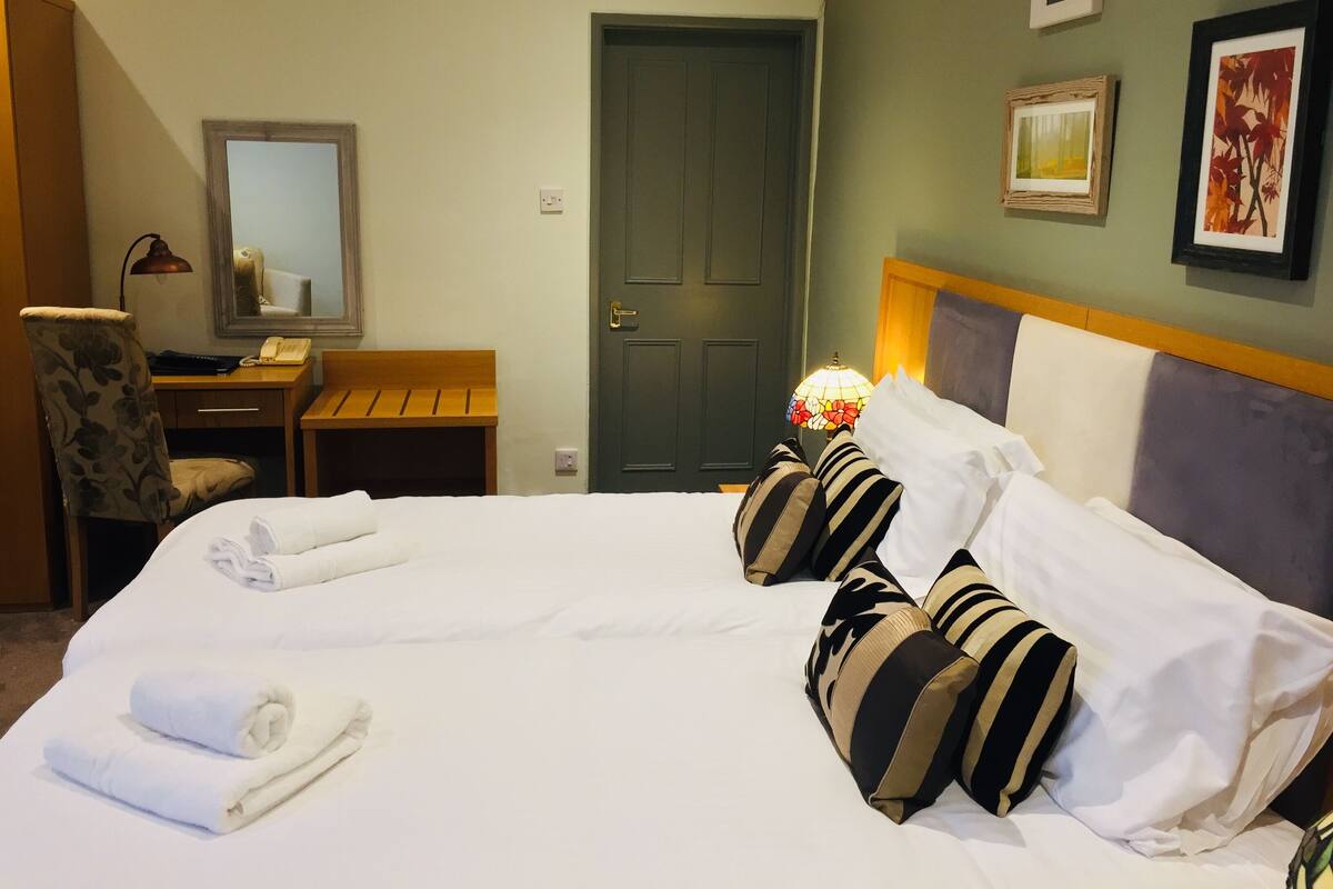 A hotel room with a bed, a desk, a chair, and a door.