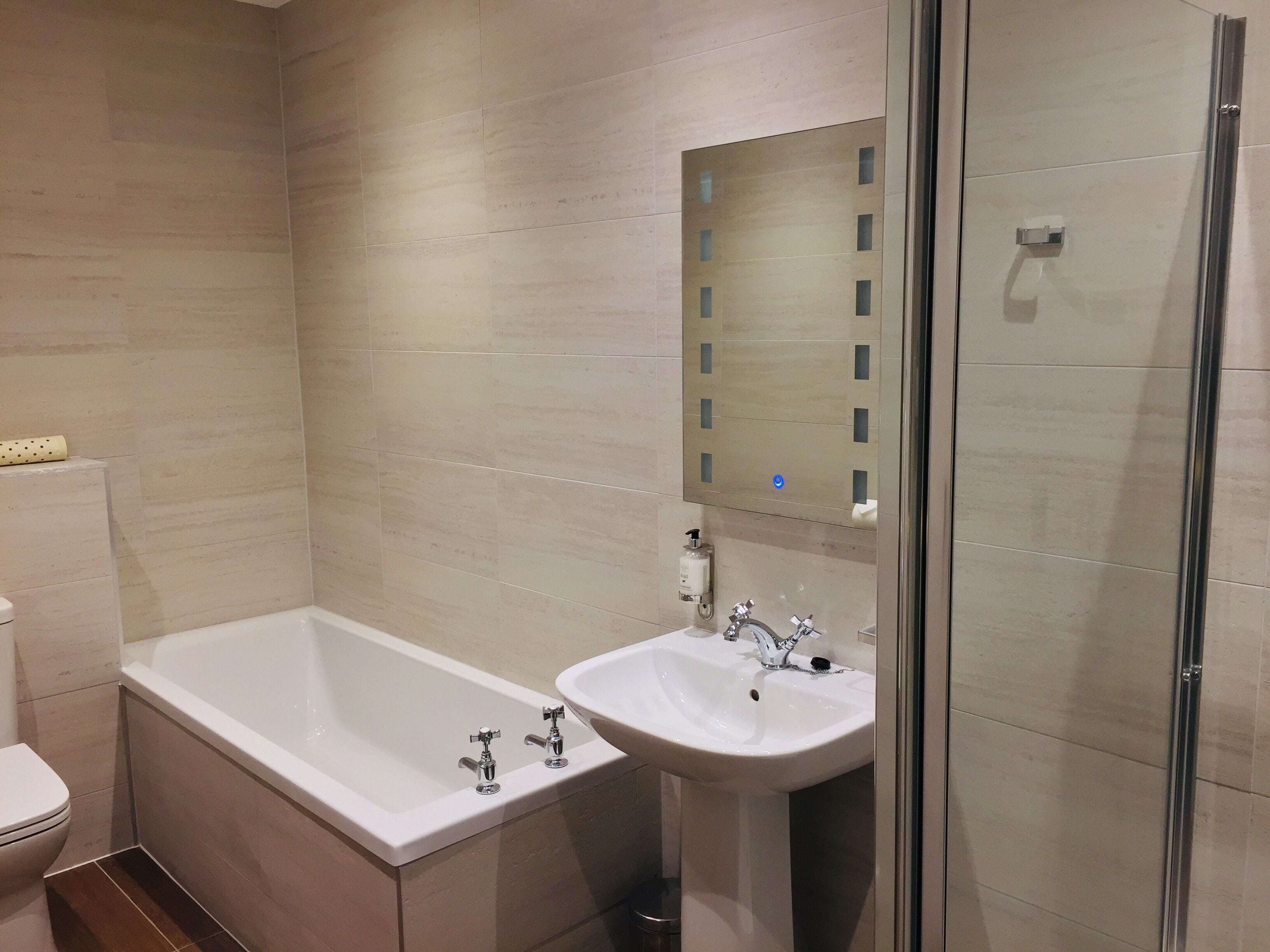 Un baño moderno con bañera, lavamanos y cabina de ducha de vidrio.