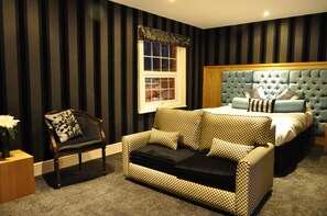 A bedroom with a large bed, a sofa, a chair, and a window.