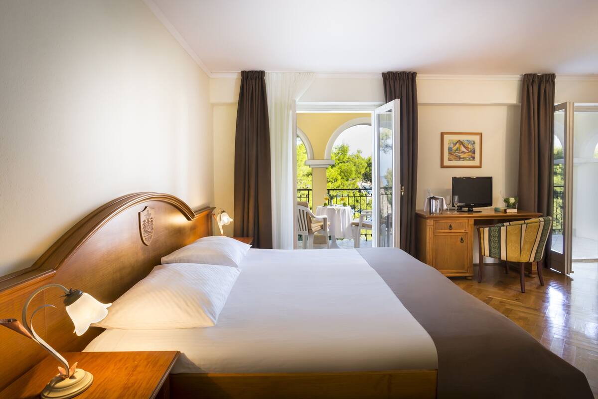 Habitación de hotel con una cama grande, un escritorio, una silla y un televisor.