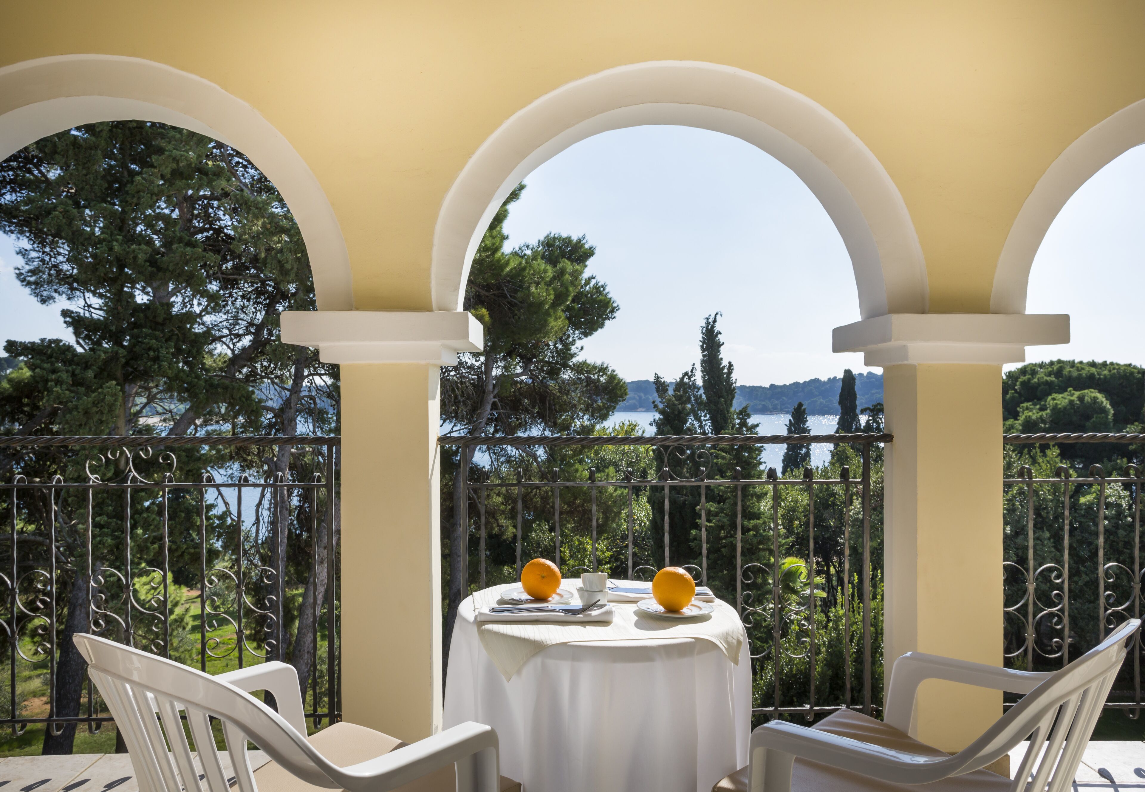 Ein Balkon mit Tisch für zwei Personen, der einen schönen Blick auf Bäume und Wasser bietet.