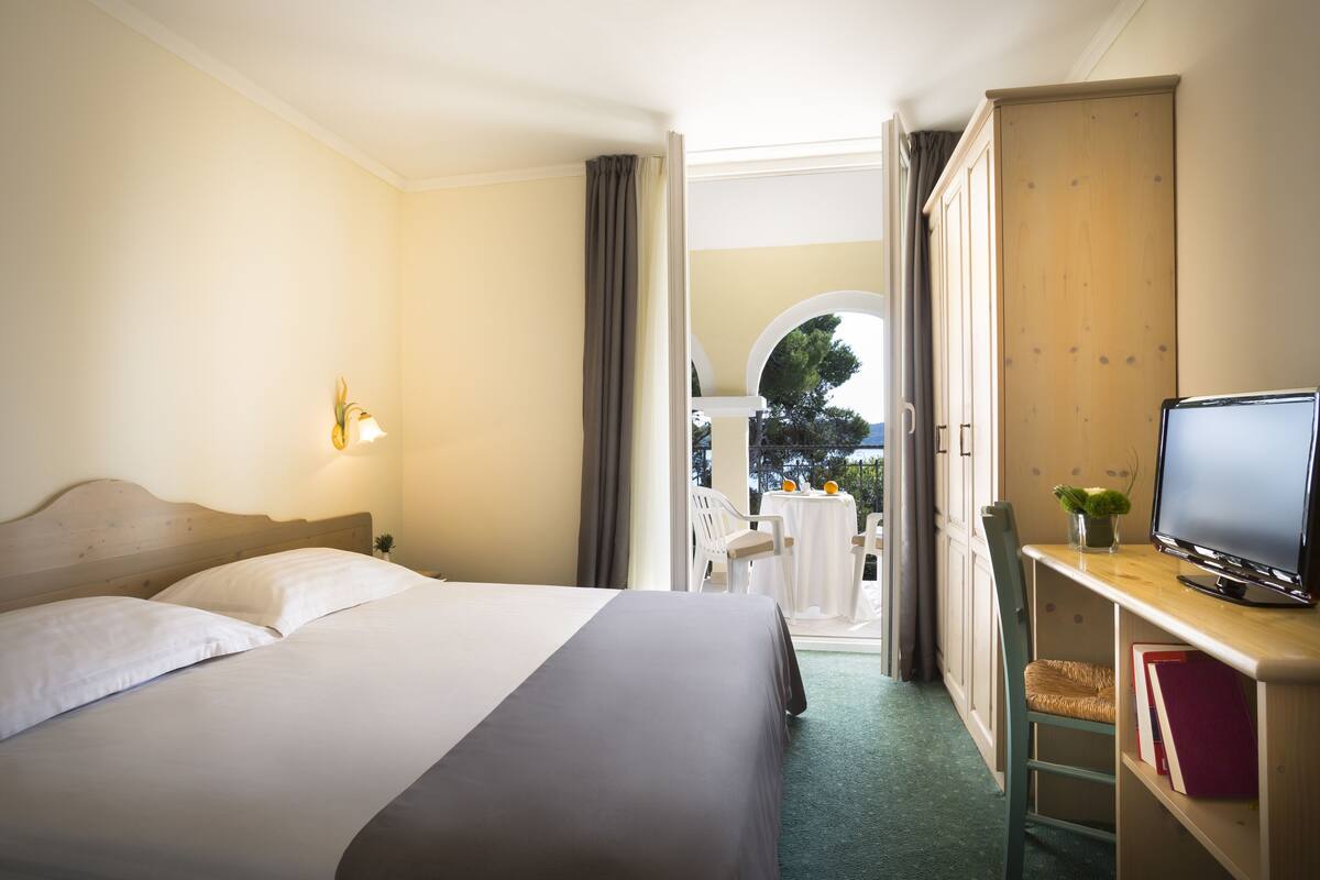 Una habitación de hotel con cama, escritorio con televisor y vistas al exterior.