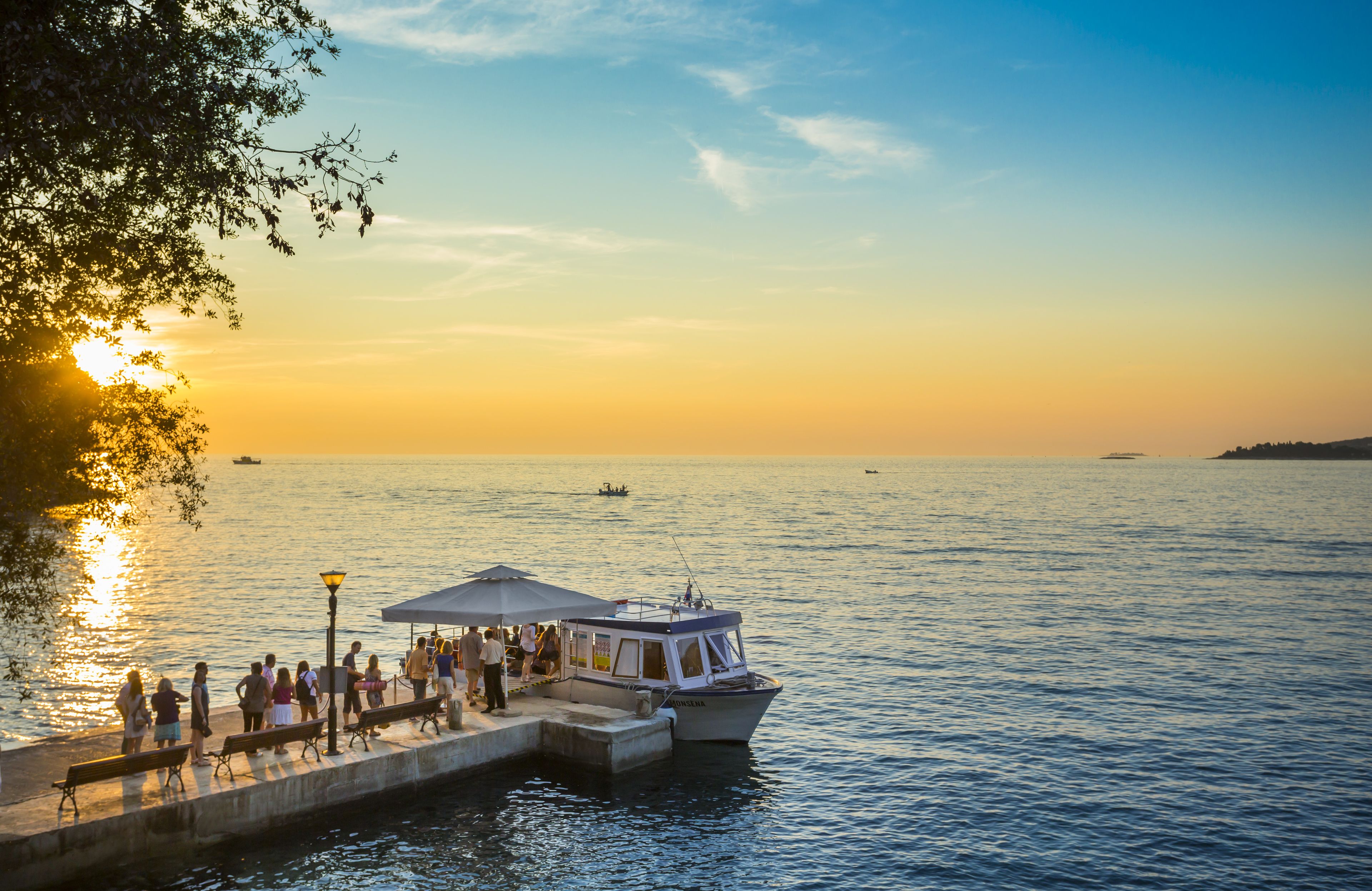 A waterfront scene with a dock, people, and a boat.