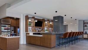 A modern bar area with wooden cabinetry, a flat-screen TV, and bar stools. - DoubleTree by Hilton Las Vegas East Flamingo (Las Vegas)