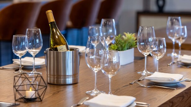A dining table set with wine glasses, a bottle of champagne, and a candle in a geometric holder. - DoubleTree by Hilton Las Vegas East Flamingo (Las Vegas)