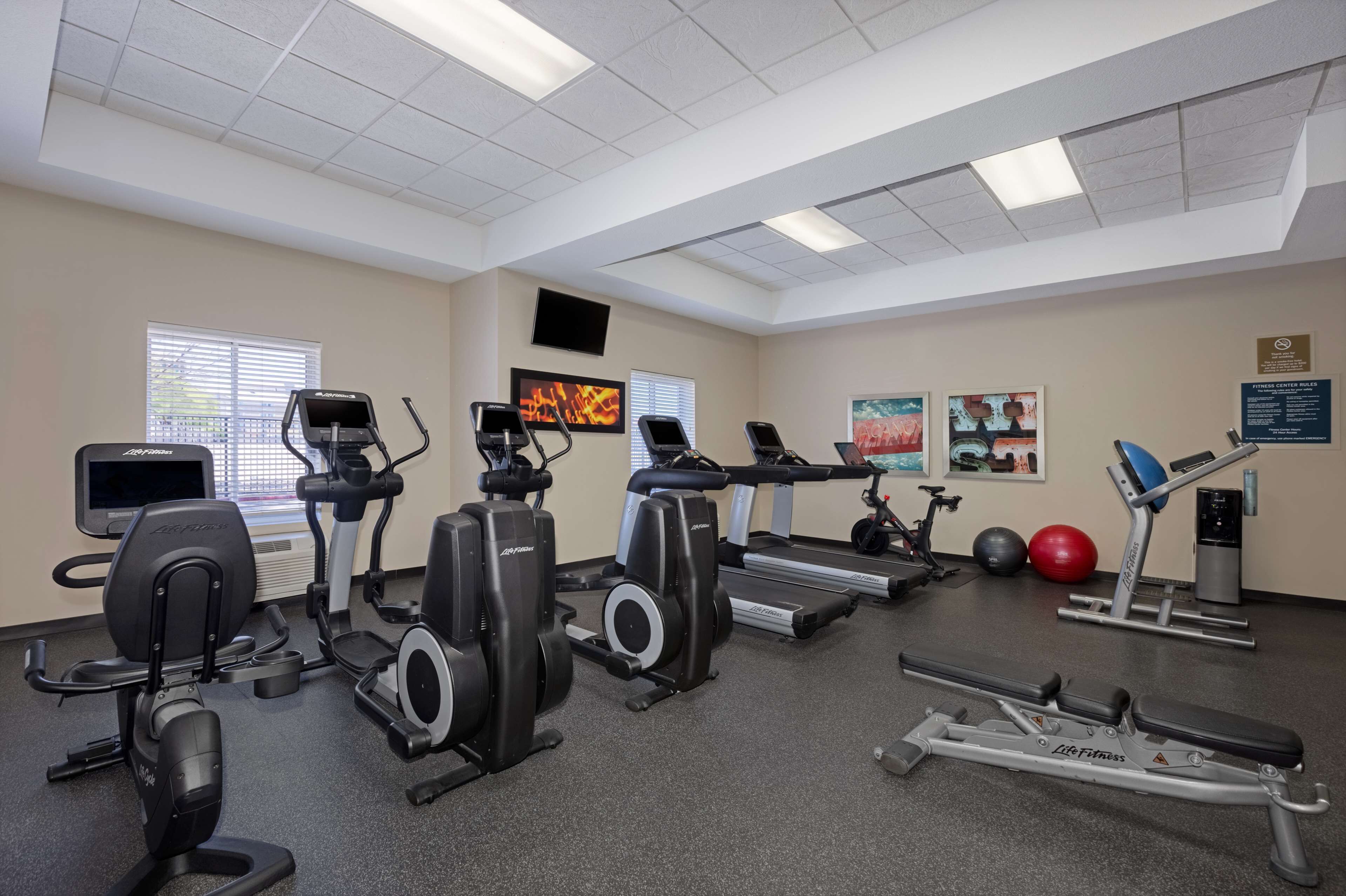 A gym with cardio machines, a treadmill, a rowing machine, and a bench press.