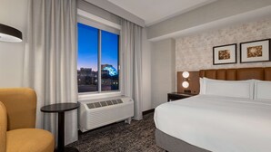 A hotel room with a large bed, a chair, a small table, a heater, and a window with a city view. - DoubleTree by Hilton Las Vegas East Flamingo (Las Vegas)