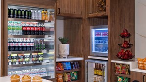 A kitchenette with a refrigerator stocked with beverages, snacks, and a microwave. - DoubleTree by Hilton Las Vegas East Flamingo (Las Vegas)