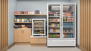 A small kitchenette with a refrigerator and freezer, stocked with various food items and beverages.