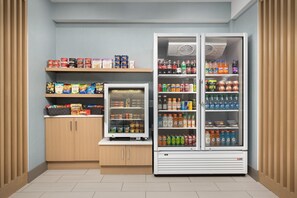 Uma pequena cozinha compacta com geladeira e freezer, repleta de alimentos e bebidas diversas.