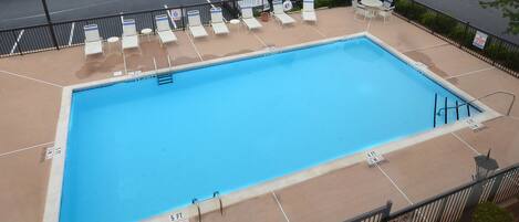 A rectangular pool with a blue interior, surrounded by a tiled deck.