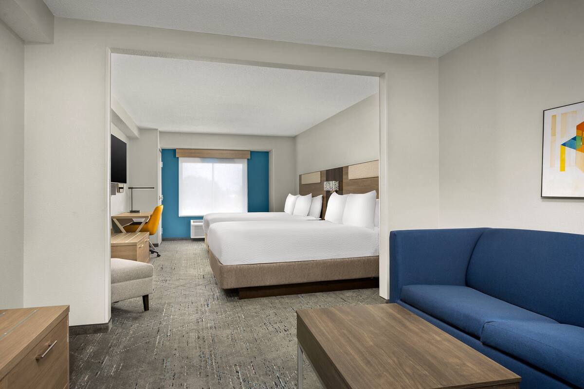 A hotel room with a bed, a blue sofa, a desk, and a chair.