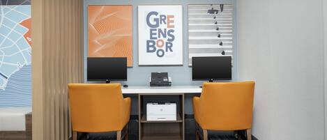 A modern office space with two desks, two chairs, and three framed artworks on the wall.