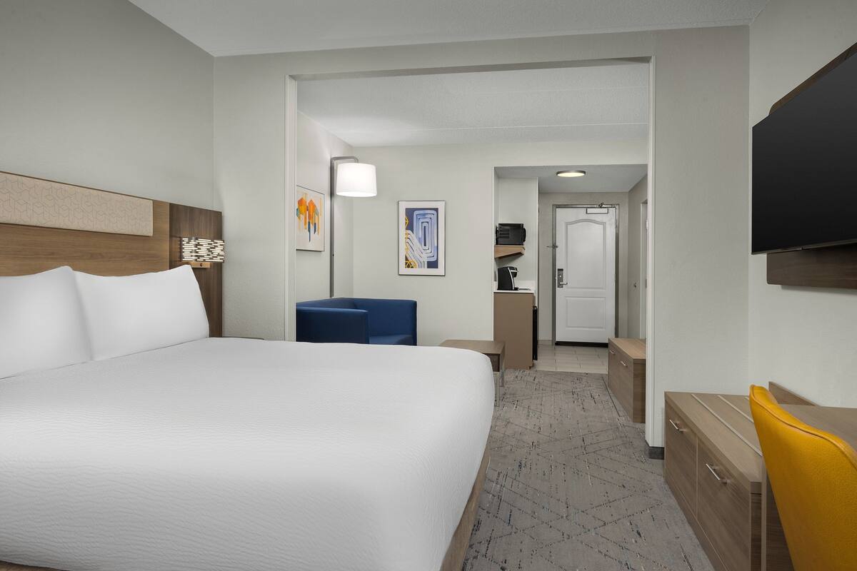 A hotel room with a large bed, a desk, a chair, and a television.