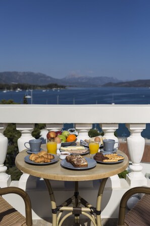 A round table with breakfast items and a view of the sea.
