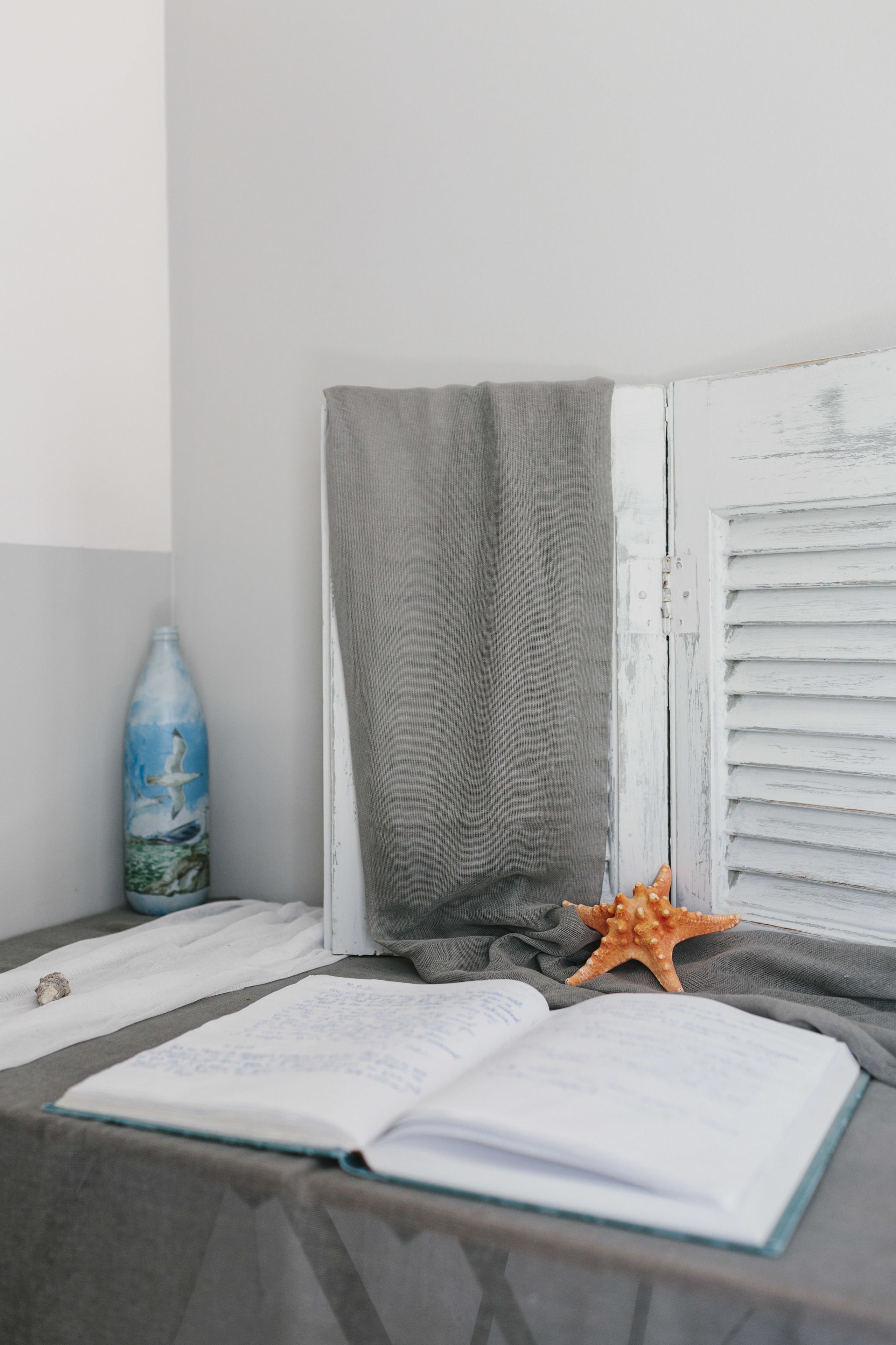 A room with a window, a book, a bottle, and a starfish.