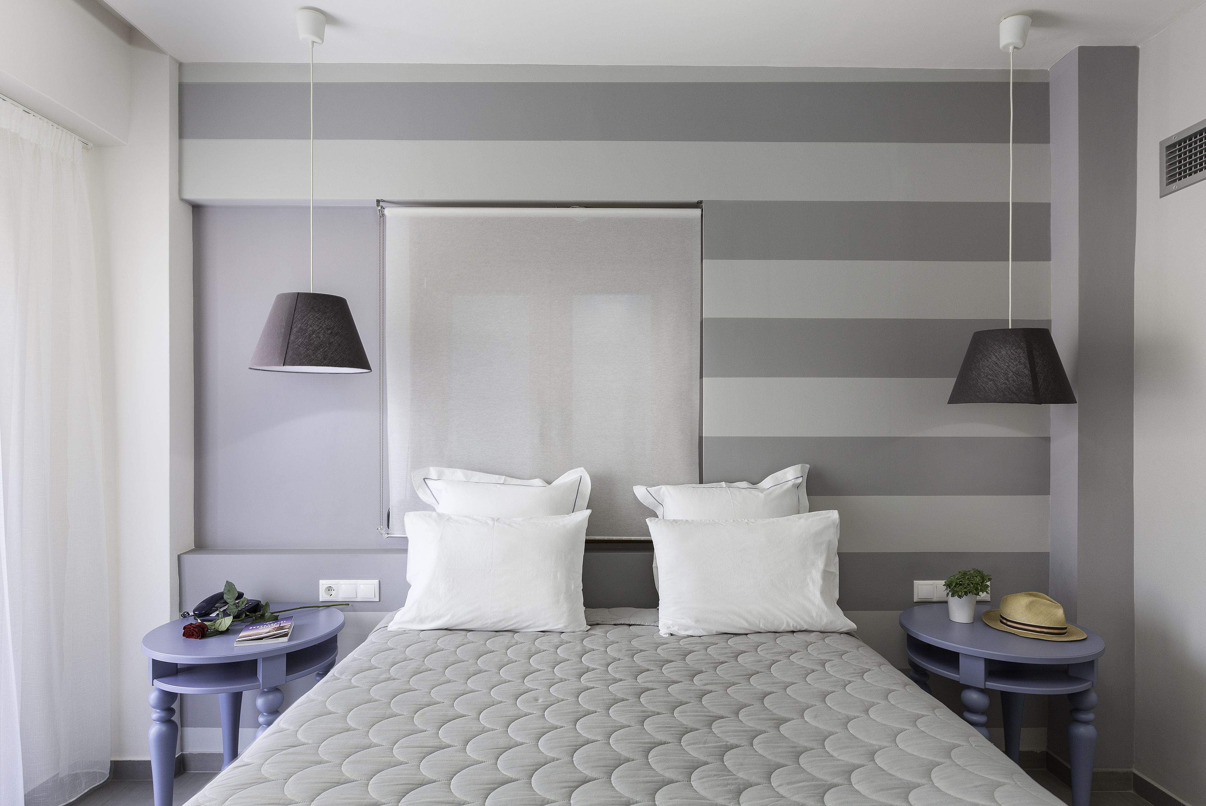 Un dormitorio moderno con una cama grande, dos mesitas de noche, una lámpara colgante y una ventana con cortinas.