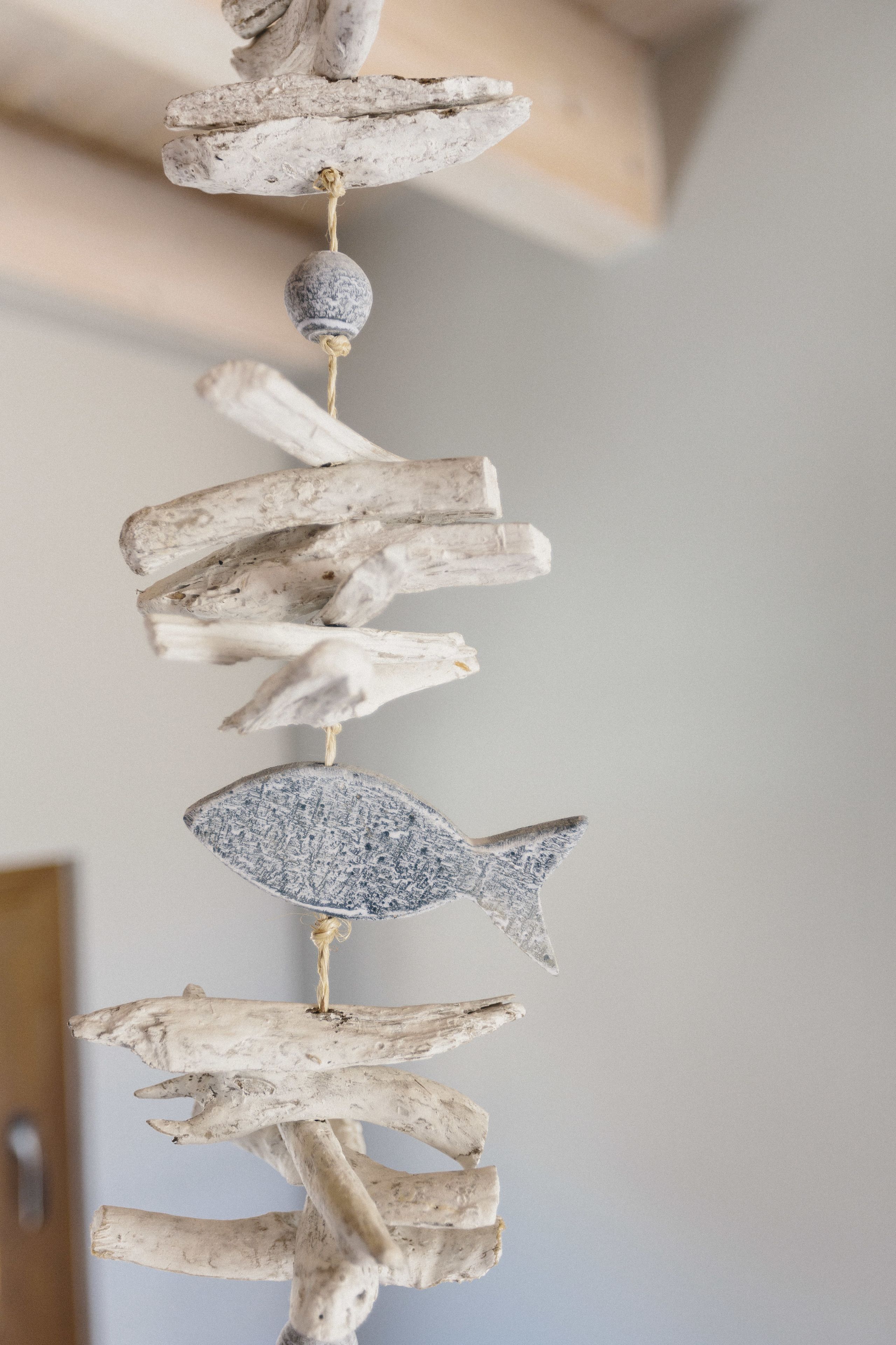 A vertical arrangement of natural elements, including driftwood and a textured sphere, suspended from a ceiling.