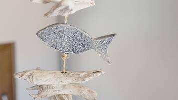 A vertical arrangement of natural elements, including driftwood and a textured sphere, suspended from a ceiling.