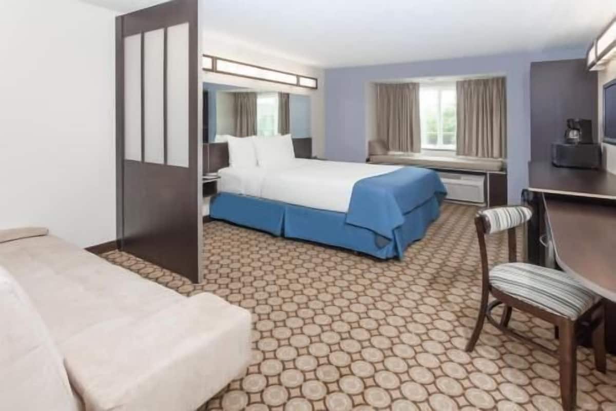 A hotel room with a bed, a desk, a chair, and a window.
