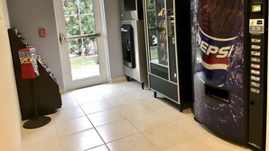 A vending machine area with a Pepsi dispenser, a fire alarm, and a door with an exit sign.