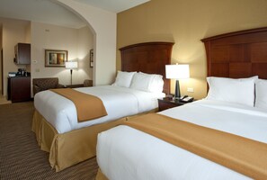 Een hotelkamer met twee bedden, een bureau, een stoel, een lamp en een telefoon.