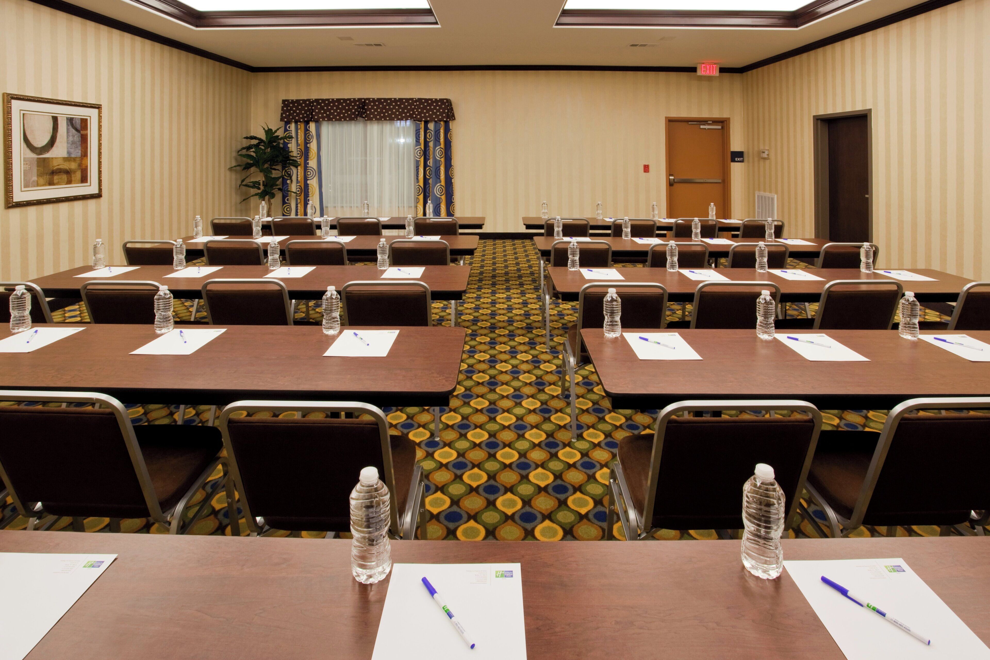 A conference room with multiple tables, chairs, water bottles, and papers.
