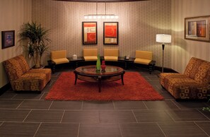 A conference room with a round table, four chairs, a red rug, and two paintings on the wall.