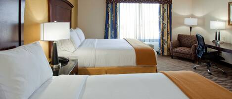 Quarto de hotel com duas camas, uma escrivaninha, uma cadeira e janela com cortinas.