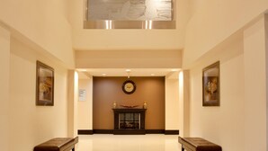 A spacious lobby with a high ceiling, a fireplace, and two benches.