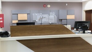 A reception desk with a wooden counter, a computer monitor, and a sign for Holiday Inn Express & Suites.