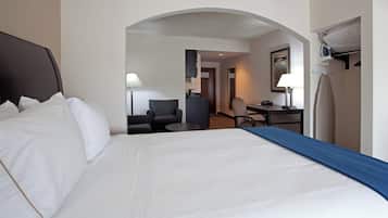 Una habitación de hotel con una cama grande, un escritorio, una silla y una pequeña cocina.