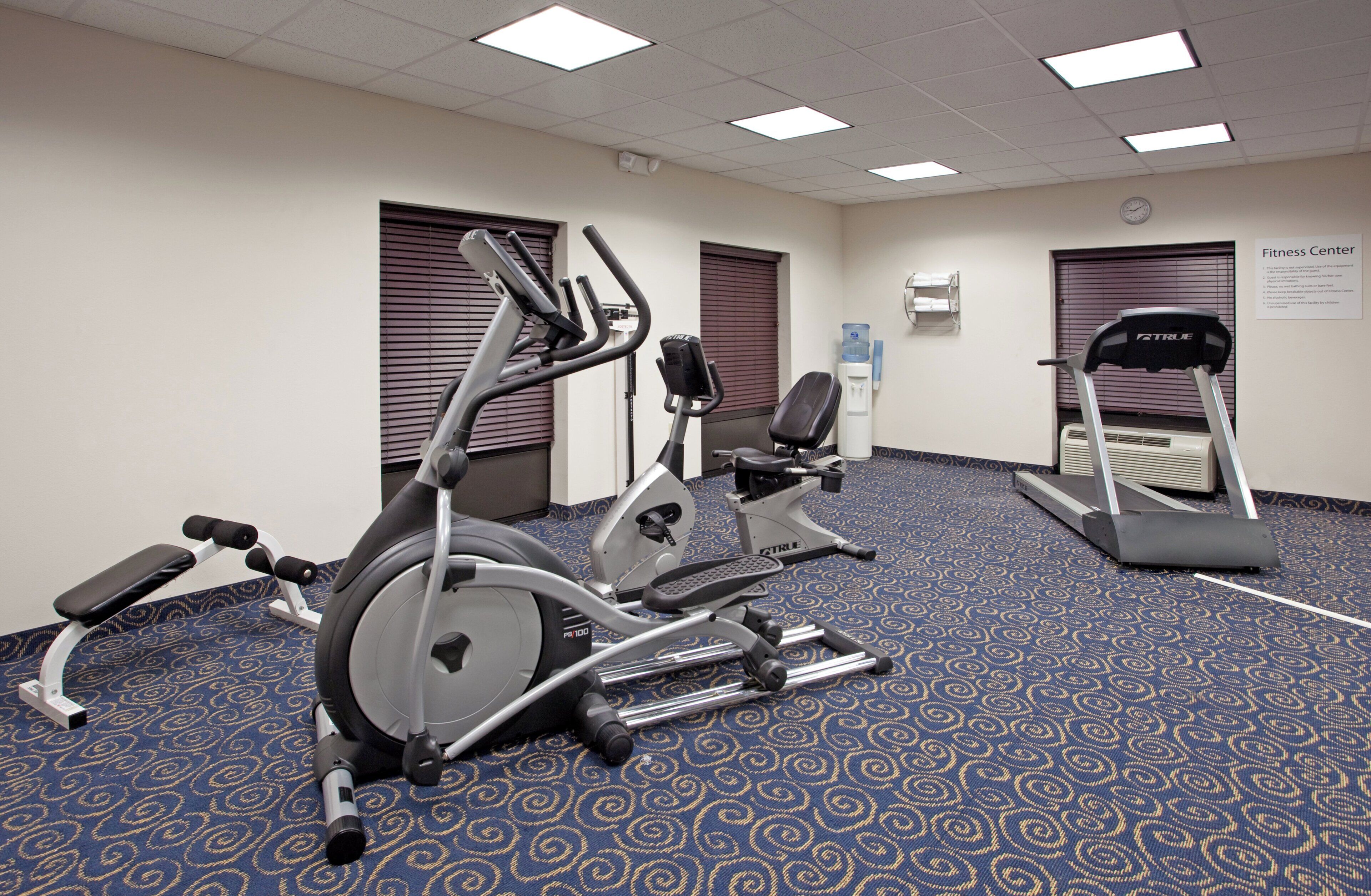 A fitness center with exercise equipment including treadmills, elliptical machines, and a stationary bike.