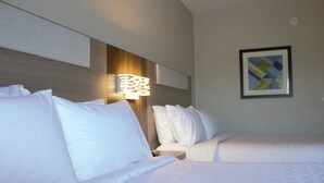 A hotel room with two beds, a headboard with a light fixture, and a framed abstract art piece on the wall.
