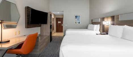 Una habitación de hotel con escritorio, una silla naranja, una cama, un televisor y una puerta que da a otra habitación.