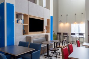 A modern restaurant with high ceilings, blue and grey walls, and a variety of seating options including tables, booths, and chairs. - Holiday Inn Express Crystal River by IHG (Crystal River)