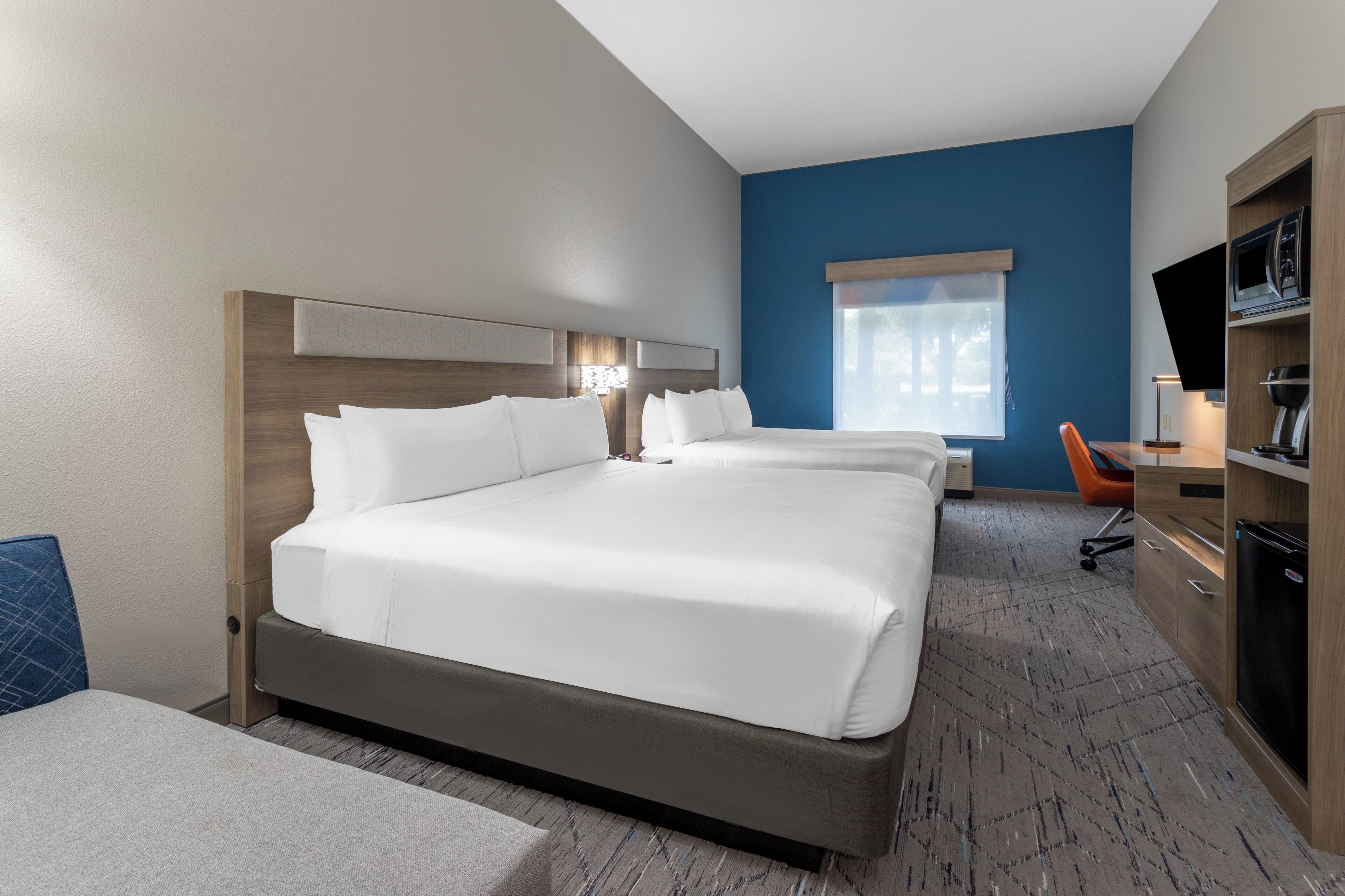 A hotel room with a large bed, a desk, a chair, and a TV.