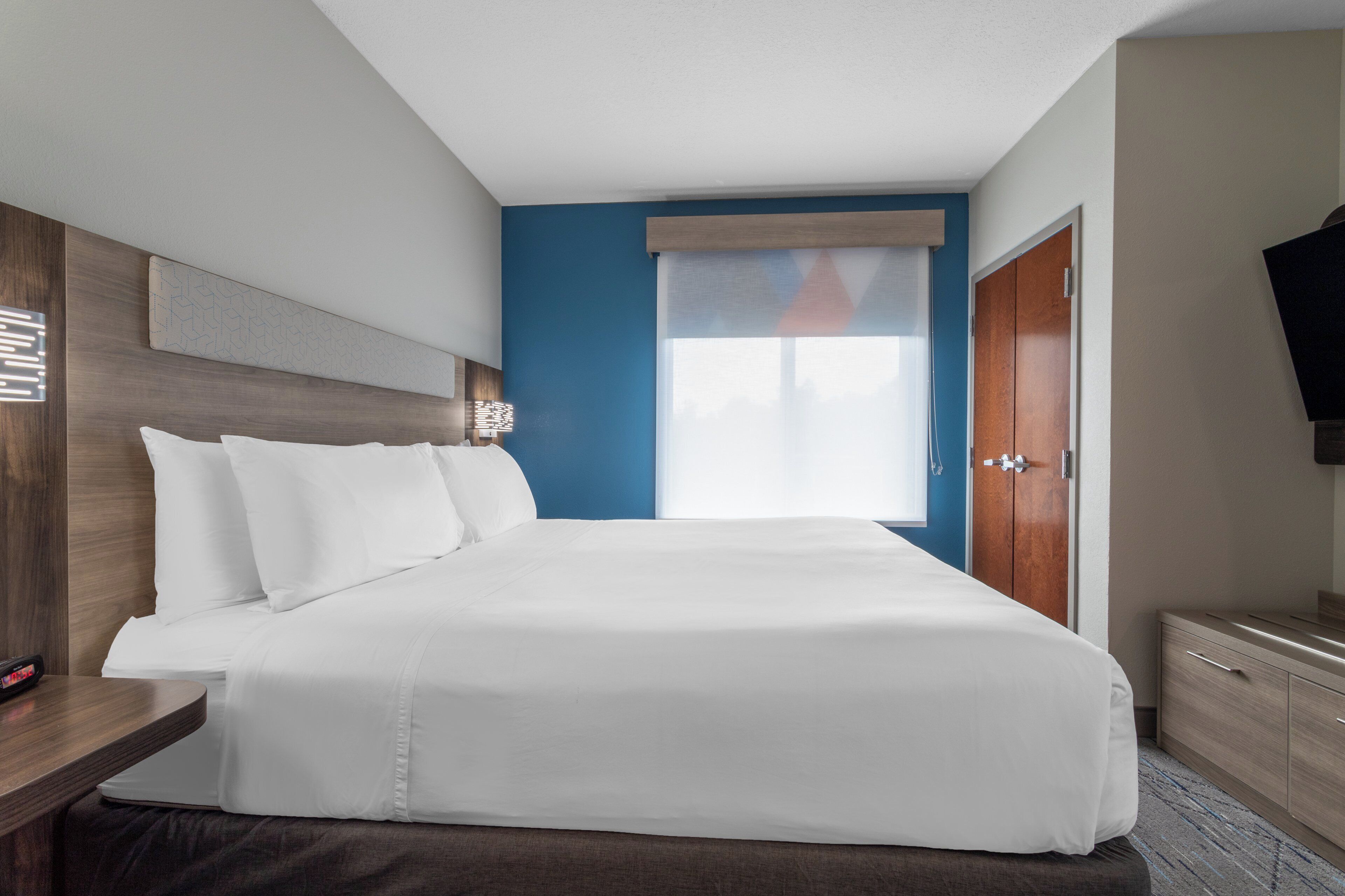 A hotel room with a bed, a nightstand, a TV, and a wardrobe.