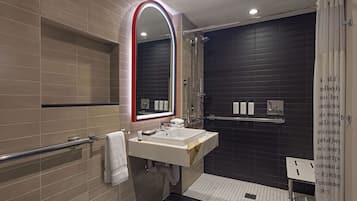A modern bathroom with a large mirror, a sink, and a shower area.