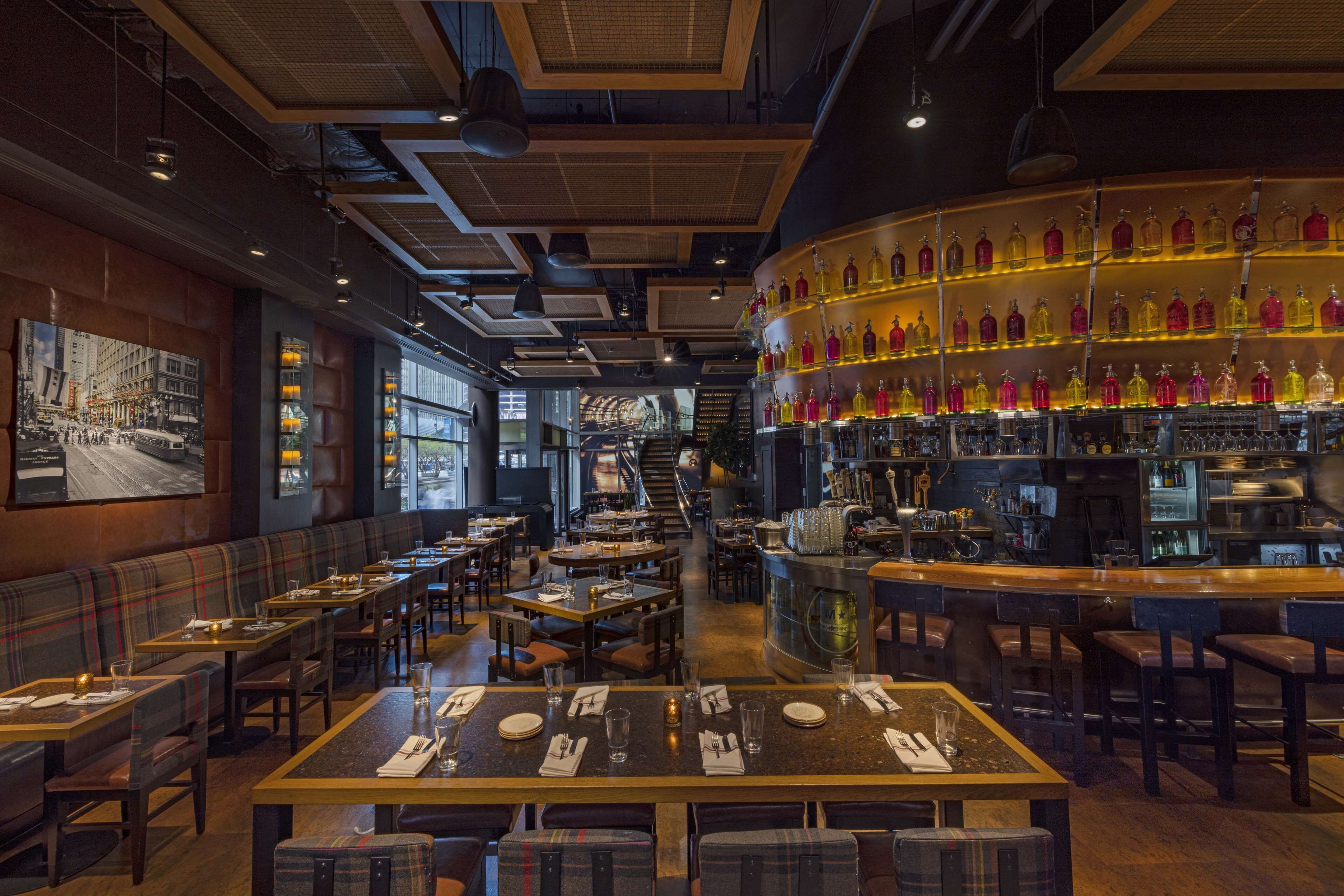Un restaurant doté d’un bar, de tables et d’une grande fresque murale.