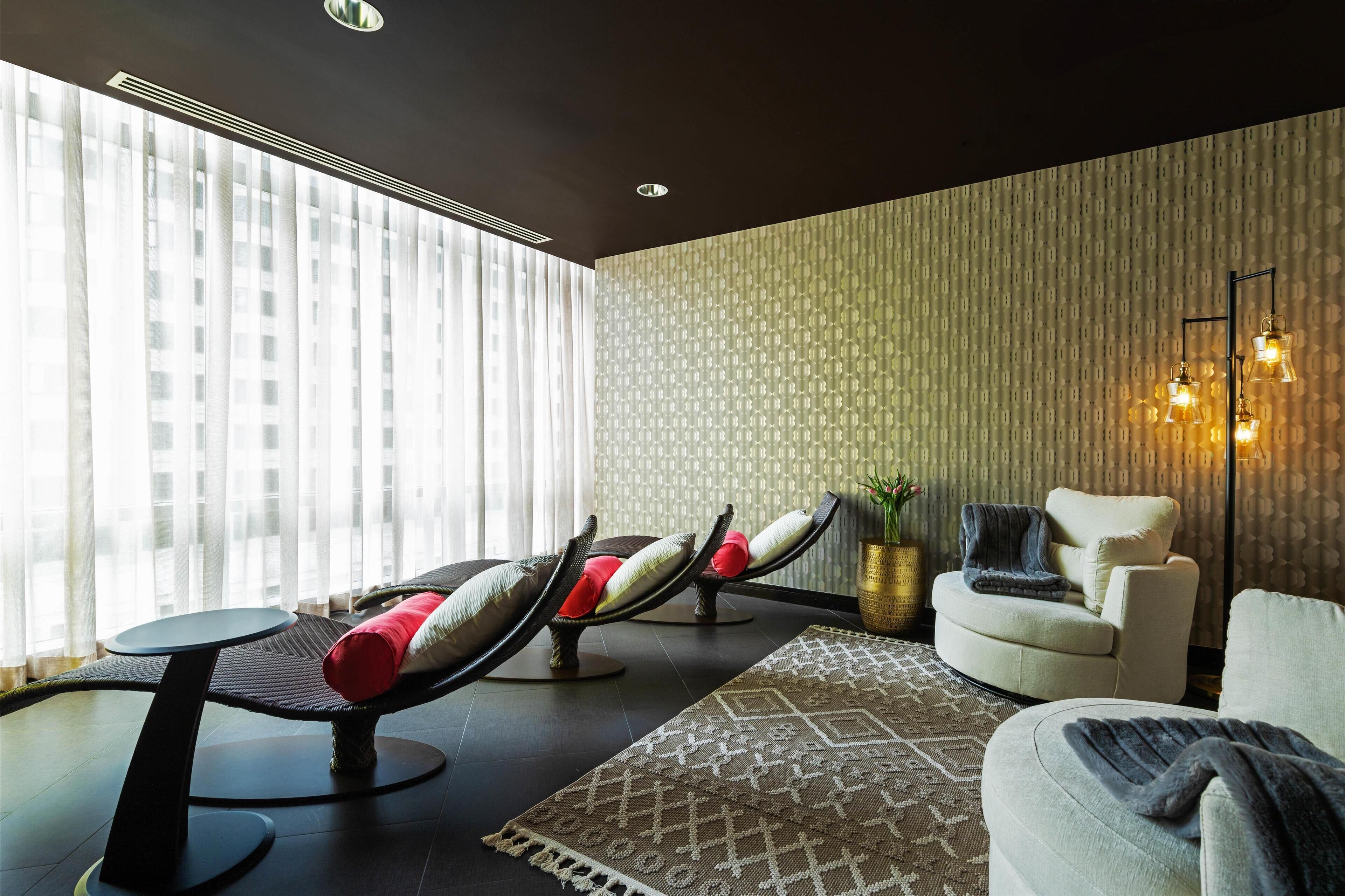 A modern room with a massage chair, a sofa, and a small table.