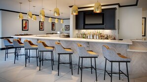 A modern kitchen with a bar area, featuring a marble countertop, bar stools, and pendant lighting.