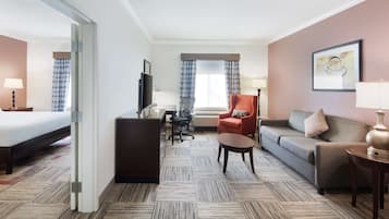 Una habitación de hotel con cama, escritorio, sofá, sillón y televisor.